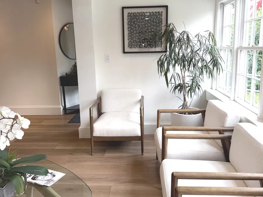 The waiting room, with white armchairs, fresh orchids and a glass coffee table.